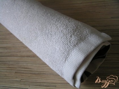 Перевернуть бисквит другой стороной (бумагой к полотенцу) на подготовленное полотенце и аккуратно свернуть в рулет. Оставить до полного остывания.