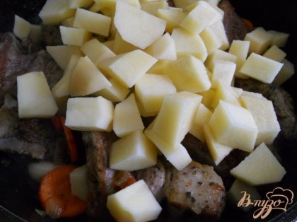 Далее добавить морковь, порезанную кружками (тушить 3-4 минуты), целые зубки чеснока и картофель порезанный кубиками.