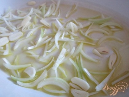 Форму для запекания смазать оливковым маслом и выложить первым слоем репчатый лук и чеснок.