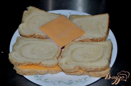 В это время обжариваем хлеб в тосторе. Выкладываем сыр пластинками, закрываем другим кусочком хлеба и ставим в микроволновку на 1 мин.