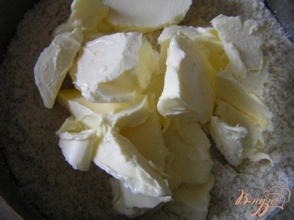 Добавить размягченное сливочное масло и сахар, хорошо перемешать, замешивая тесто.