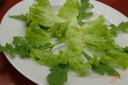 На блюдо выложить чистые листочки рукколы и листового салата.