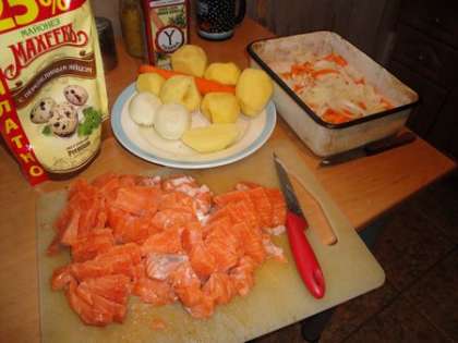 На картофель выложить слой моркови, а сверху слой лука. Рыбу порезать среднего размера квадратиками
