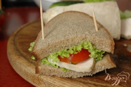 Накрыть другим ломтиком хлеба, скрепить края зубочистками. Разрезать бутерброд пополам.