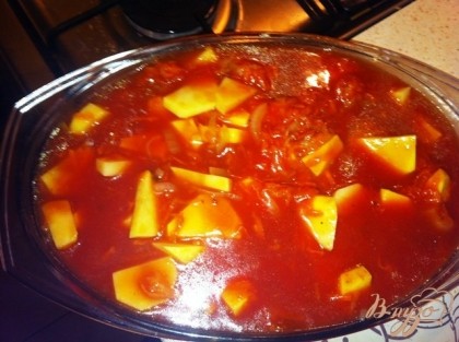 Перекладываем обжаренные овощи в огнеупорную форму, добавляем картофель и заливаем томатным соусом.
