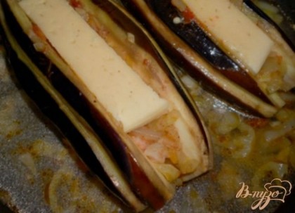 Начинить обжаренными овощами разрез в баклажанах. Сверху положить в длину по кусочку сыра. Баклажаны сложить в эту же сковороду с овощами (останутся немного). Добавить кипяченой воды (50-70 мл), подсолить чуть-чуть.