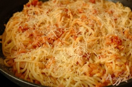 В спагетти добавить томат с грудинкой и луком, перемешать и выложить готовую массу в форму. Посыпать свеженатертым пармезаном.