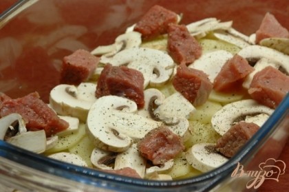 В форму со сметаной и луком выложить слой картофеля, затем немного грибов и мяса. Посолить и поперчить.