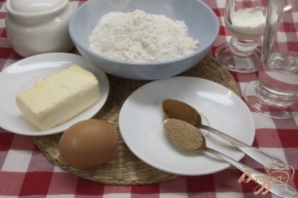 Для приготовления печенья необходимо подготовить основные продукты: яйцо, муку, масло, сахар, дрожжи, воду, сметану и корицу.
