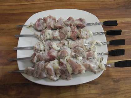 Когда мясо промаринуется, нанизать его на шампуры, чередуя колечки из лука и кусочки мяса