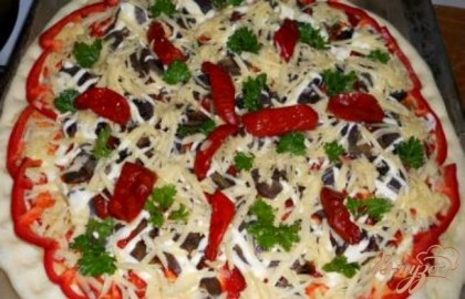 Далее - тертый сыр, сверху вяленые помидоры, по краю выложить кусочки болгарского перца, посыпать немного зеленью. Выпекать пиццу в разогретой до 220 градусов духовке 15-20 минут.