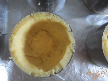 На протвень с фольгой установить порционные круги, смазав стенки оливковым маслом.Выложить картофельную массу так, чтобы получилось дно и бортики.