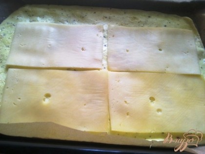 Достаем готовый омлет из духовки, выкладываем пластинки сыра и посыпаем зеленью