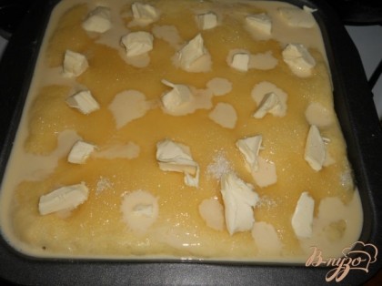 Залить смесью пирог, обильно посыпать сахаром (5 столовых ложек). Разложить по поверхности пирога кусочки сливочного масла.
