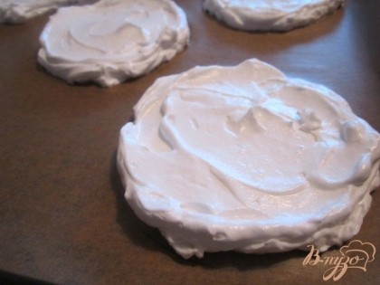 На листе пекарской бумаги начертить круги и выложить первый слой крема.