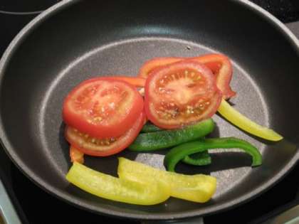 Положить на сковородку помидоры и перцы, обжарить на маленьком огне перемешивая примерно 1,5 минуты