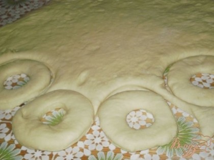После того, как тесто увеличилось, раскатываем его в пласт толщиной примерно 1 см и вырезаем пончики.