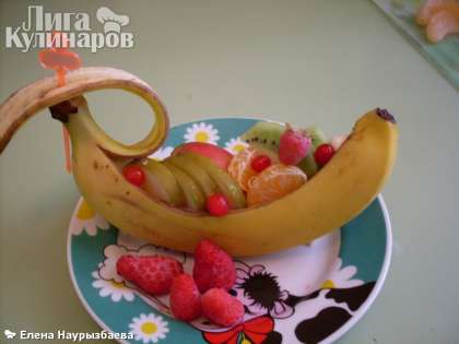 Все фрукты укладываем в банан-кораблик. Украшаем ягодой.  Отрезанную часть банана (то есть его кожуры) прикалываем зубочисткой или шпажкой.