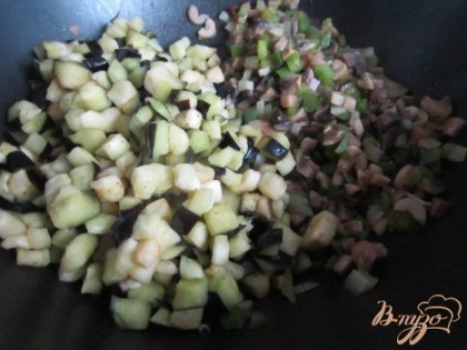 Затем грибы, томат и отжатые кусочки баклажана.Посолить и поперчить по вкусу. Накрыть крышкой и потушить 10  мин.