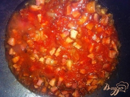 Добавляем помидорную массу к обжаренной ветчине с луком и чесноком. Тушим несколько минут и посыпаем базиликом, перцем и солим по вкусу.