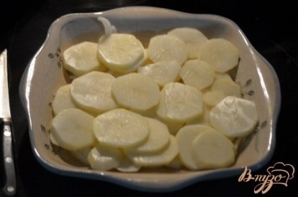 Порежем пластинками картофель и лук. Выложим слоями в жаропрочное блюдо часть.