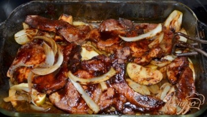 Выложить свиные отбивные поверх яблок и шалота. Вылить половину барбекю сверху. Поставить в духовку снизив тем-ру на 190 гр. на 15 мин. Перевернуть, вылить вторую часть соуса барбекю и готовить еще 15 мин. или до готовности.