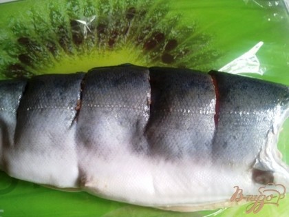 Рыбку кладем на пищевую пленку с двух сторон делаем надрезы.