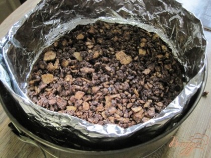 Приготовить прослойку.Шоколад с орехами растопить на водяной бане.Миндаль порубить,60г вафель истолочь в крошку и смешать с растопленным шоколадом.Выложить на бисквит и хорошо разровнять.