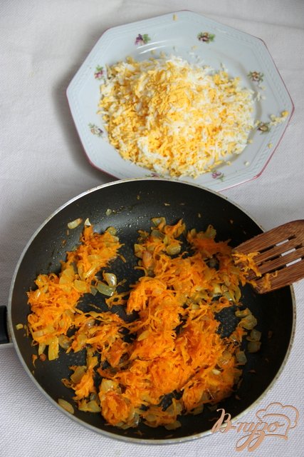  Параллельно. Отварить яйца и натереть на мелкой тёрке. Спассеровать лук и морковь на смеси растительного и сливочного масел.