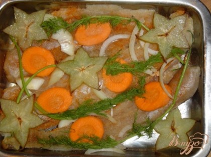 Противень смазываем растительным маслом.На него выкладываем рыбу,предварительно посыпав ее специями.Сверху рыбки выкладываем лук,морковь,зелень и нарезанную поперек карамболу.