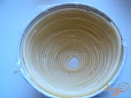 Салатник в виде полусферы ( у меня 2 штуки Ф-12см)  застелить изнутри пищевой пленкой и смазать тонким слоем растительного масла. Выложить дно и стенки салатника макаронами в виде спирали, начиная со дна.