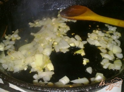 В сковороде разогреть растительное масло и обжарить репчатый лук с чесноком до прозрачности.