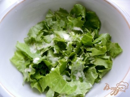 Салат предварительно помыть, обсушить и положить в холодильник. В холодном виде он более хрустящий и дольше сохраняет свежесть. Охлажденный салат порвать руками в салатник, полить немного соусом и перемешать.