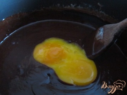  Шоколадную смесь снять с огня и ввести желтки, быстро их размешать.