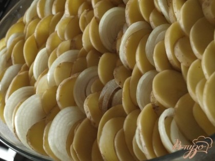 Форму смазать маслом и вертикально разложить картофель с луком рядами.
