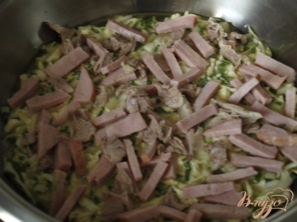 Разогреваем сковороду,смазываем маслом,выкладываем половину капустной смеси,затем нарезанное мясо или ветчину.