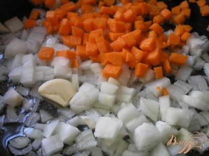 В смеси растительного и сливочного масел обжарить на медленном огне нарезанный лук, слегка придавленный зубчик чеснока и нарезанную кубиками морковь.