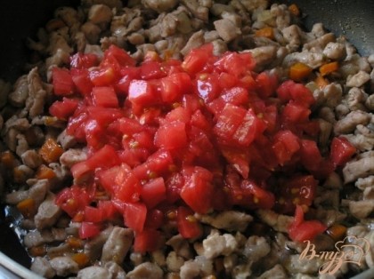 Через 2 минуты добавить очищенные от кожи и семян помидоры, нарезанные маленькими кусочками, перемешать.