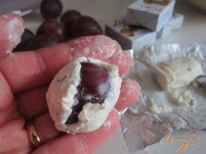 Слегка влажными руками сделать небольшую лепешку, уложить виноградину и обмазать ее со всех сторон сыром.