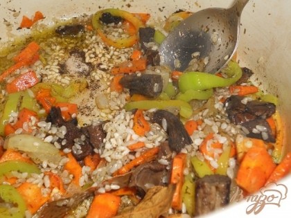 Добавить к пассированным овощам рис и вымоченные грибы,обтушить 5-6 минут и все залить водой, посолить,добавить лавровый лист.