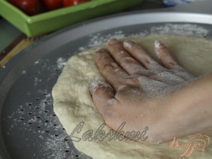 Лепёшку из теста кладём в центр формы и придавливая ладонями растягиваем тесто к краям.