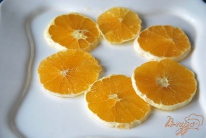 На тарелку выкладываем нарезанные кольцами апельсины.