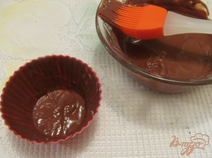 Смазать силиконовой кисточкой силиконовые формочки для кексов. Поставить в морозилку на несколько минут, чтобы шоколад застыл.