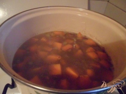 В кастрюлю налить 1,5 - 2 л воды, довести до кипения. Заложить чечевицу, обжаренные овощи со сковороды, закрыть крышкой и варить 30 минут