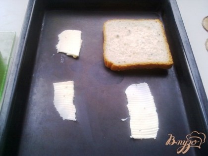 На противень под каждый кусочек тостового хлеба кладем тоненькую пластнку сливочного масла