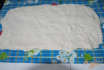 Растянем руками тесто в пласт размером приблизительно 30 на 50 см, если липнет, подсыпьте муки.