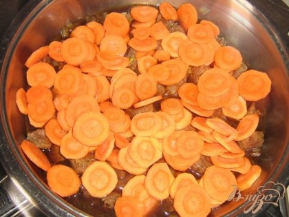 Морковь нарезать кружочками и выложить в сковороду к мясу.