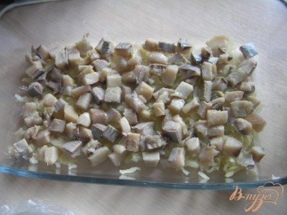 На дно формы потереть немного картофеля, выложить нарезанное филе сельди,