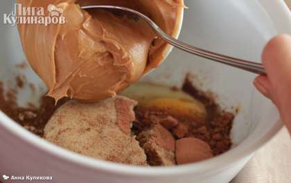 Если арахис у вас не жареный, обжарьте его, помешивая, на сухой сковороде в течение 15 минут. Затем в блендере превратите его в муку, добавьте сахарную пудру и рафинированное масло. Взбейте.  В миску разбейте яйцо, добавьте коричневый сахар, какао, корицу и имбирь и выложите арахисовую пасту