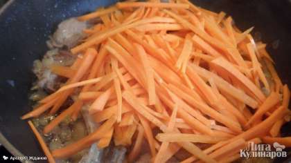 И нарезанную соломкой морковь. Помешивая, обжарьте в течение 10-15 минут